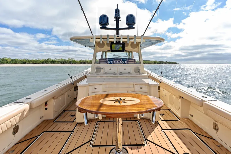 Off Line Yacht Photos Pics 2023 HCB 53 Suenos RXV luxury boat interior with wooden deck and table, ocean view.