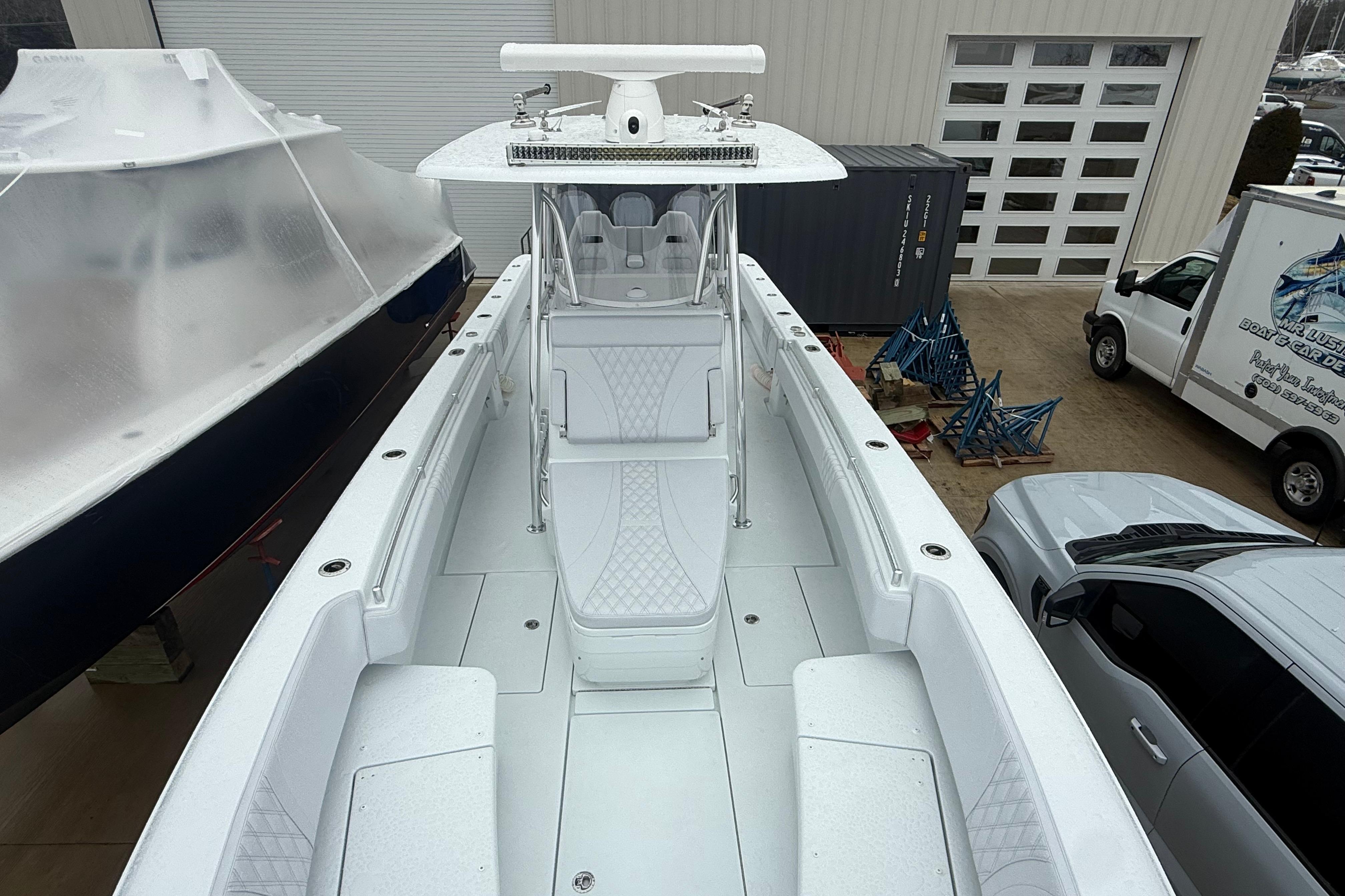 2026 Contender 35 ST boat, white interior, docked near vehicles and a building.