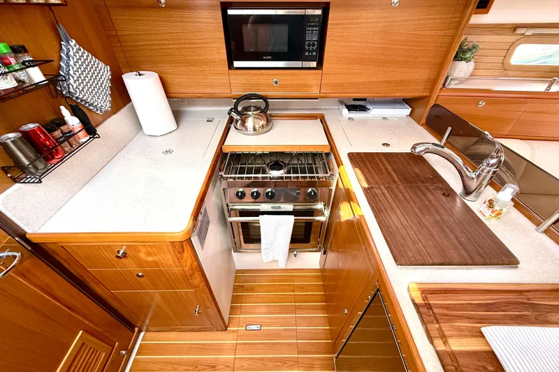 Nereid Yacht Photos Pics Modern Catalina 425 yacht kitchen with wooden cabinetry, stainless steel appliances, and ample counter space, 2020 model.