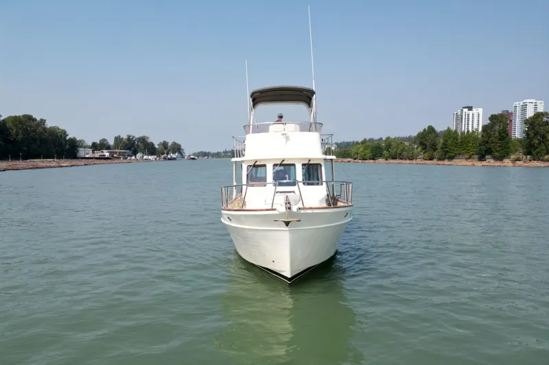 Raven Song Yacht Photos Pics 2011 North Pacific 38 Sedan cruising on a calm river with cityscape background.
