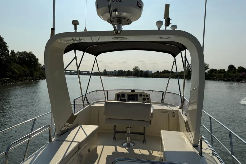 Raven Song Yacht Photos Pics 2011 North Pacific 38 Sedan boat helm with canopy on calm river.
