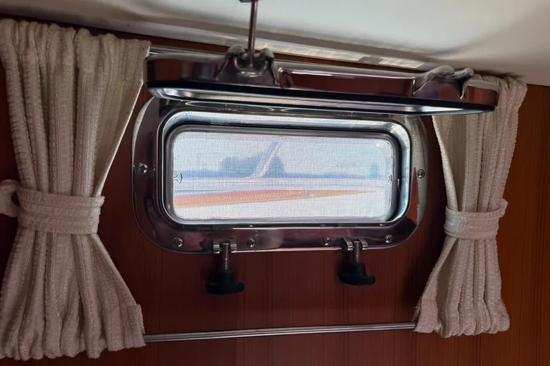 Raven Song Yacht Photos Pics Porthole window with curtains on a 2011 North Pacific 38 Sedan boat interior.