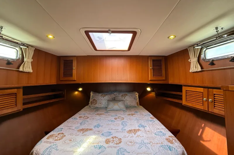 Raven Song Yacht Photos Pics Cozy cabin interior of 2011 North Pacific 38 Sedan with wood paneling and nautical bedding.