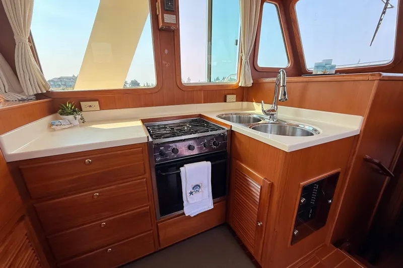 Raven Song Yacht Photos Pics 2011 North Pacific 38 Sedan kitchen with stove, sink, and wooden cabinetry.