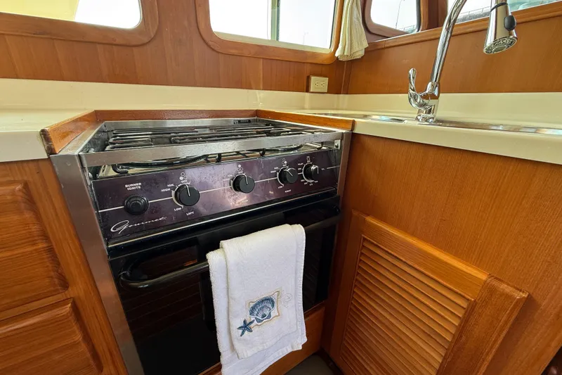 Raven Song Yacht Photos Pics 2011 North Pacific 38 Sedan kitchen with stove, sink, and wooden cabinetry.