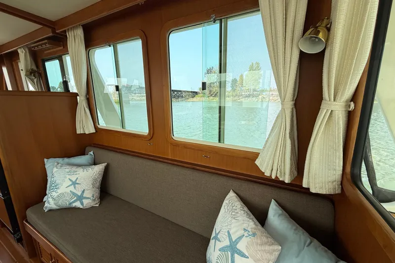 Raven Song Yacht Photos Pics Interior of 2011 North Pacific 38 Sedan with sofa, nautical pillows, and window view.