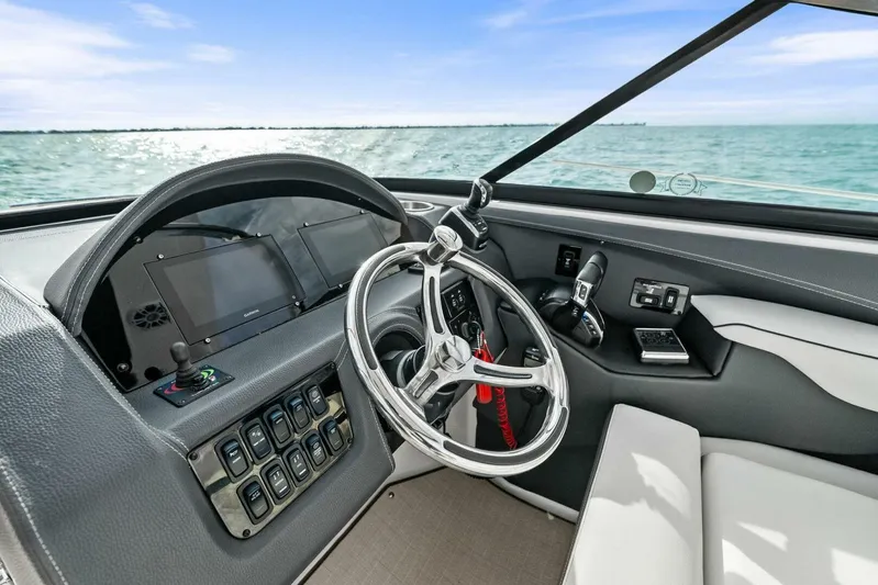  Yacht Photos Pics 2023 Regal 29 OBX boat dashboard with steering wheel and control panel, overlooking the ocean.
