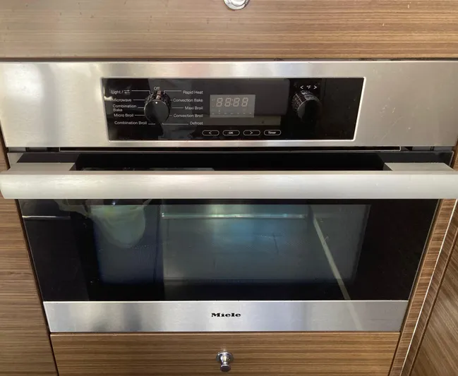  Yacht Photos Pics Modern Miele oven with digital controls and stainless steel finish in a wooden kitchen setting.