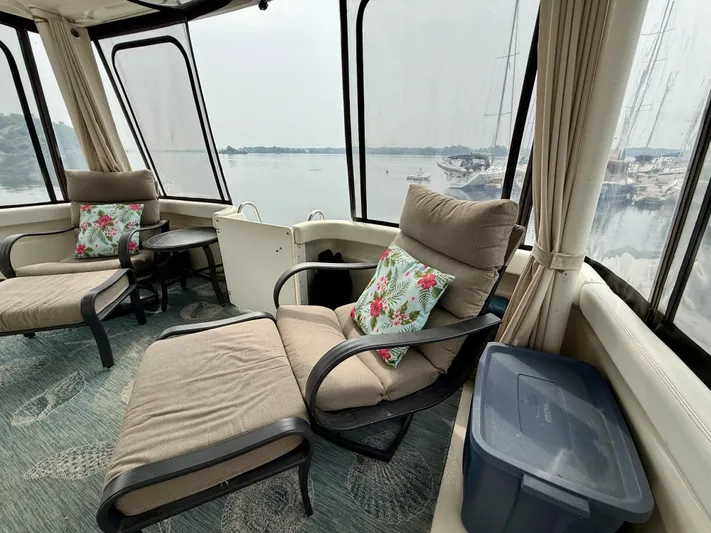  Yacht Photos Pics 1997 Silverton 402 Motor Yacht interior with cushioned seating and floral pillows, overlooking a serene marina.