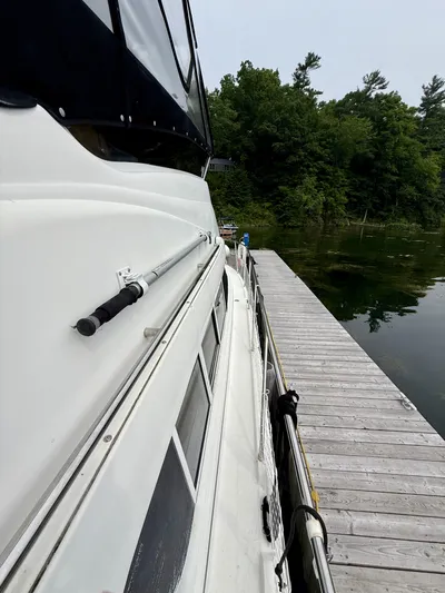  Yacht Photos Pics 1997 Silverton 402 Motor Yacht docked beside a wooden pier, surrounded by lush greenery.