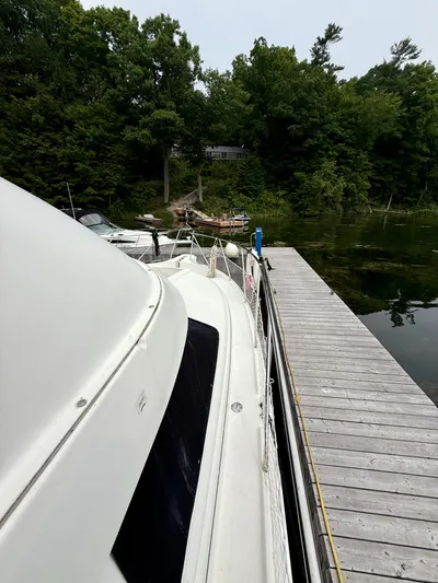  Yacht Photos Pics 1997 Silverton 402 Motor Yacht docked beside a wooden pier, surrounded by lush greenery.