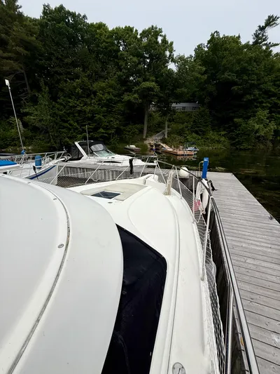  Yacht Photos Pics 1997 Silverton 402 Motor Yacht docked by a wooden pier, surrounded by lush greenery.