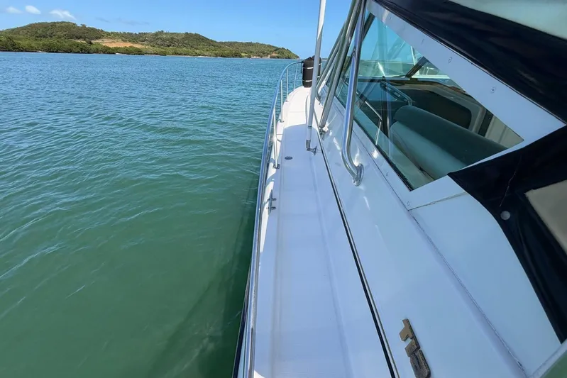  Yacht Photos Pics 1999 Tiara Yachts 4100 Open cruising on calm waters near lush green hills.