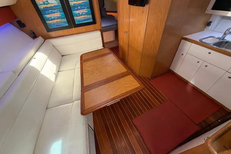  Yacht Photos Pics Interior of 1999 Tiara Yachts 4100 Open with white seating, wooden table, and kitchenette.