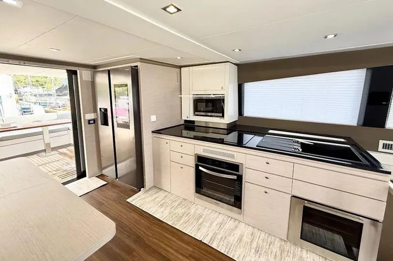  Yacht Photos Pics Modern kitchen interior of 2026 Aventura 56 MY yacht with sleek appliances and wood flooring.