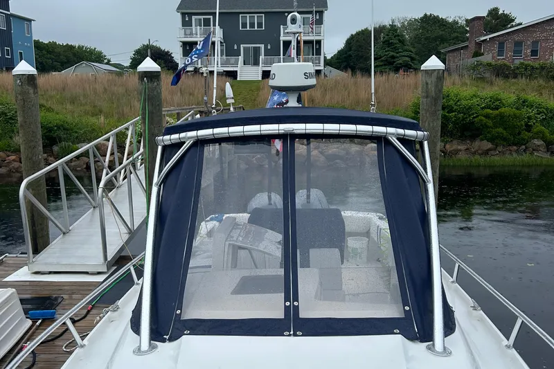  Yacht Photos Pics 2003 Intrepid 310 Walkaround boat docked, featuring a covered cockpit and nearby residential backdrop.