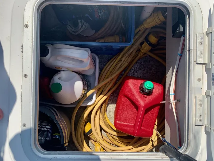 Tranquility Base Yacht Photos Pics Storage compartment with fuel can, cables, and cleaning supplies on a 2003 PDQ-34 boat.