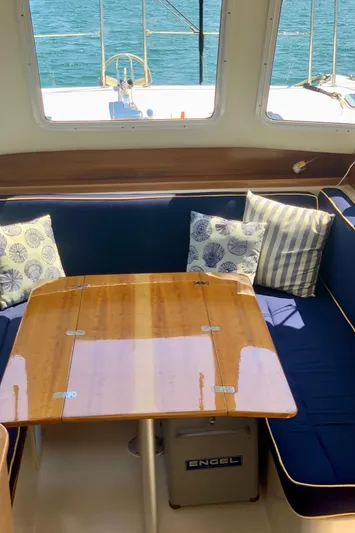 Tranquility Base Yacht Photos Pics Interior of 2003 PDQ-34 boat with blue seating, wooden table, and decorative pillows.