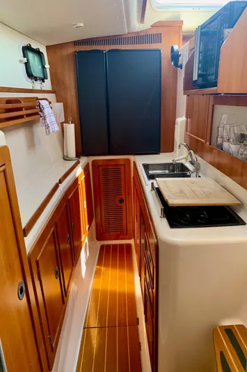 Tranquility Base Yacht Photos Pics Compact kitchen in 2003 PDQ-34 boat with wooden cabinets and modern appliances.