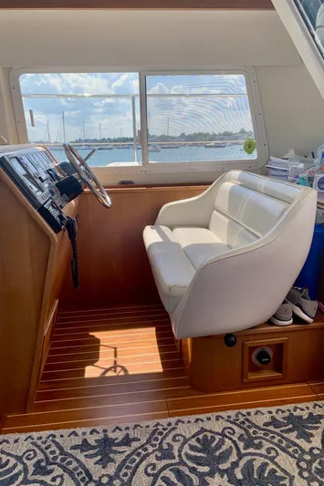 Tranquility Base Yacht Photos Pics Helm station of 2003 PDQ-34 boat with white captain's chair and wooden flooring.