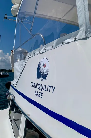 Tranquility Base Yacht Photos Pics PDQ-34 boat named "Tranquility Base" with moon logo, docked under clear blue sky.
