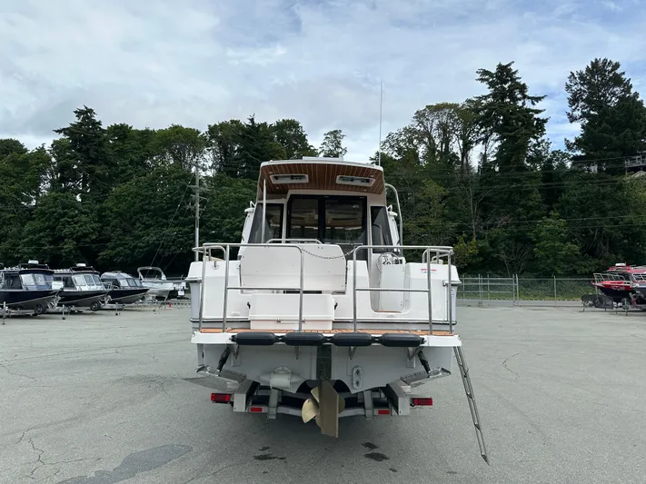  Yacht Photos Pics 2025 Ranger Tugs R29 S boat, rear view, parked in a marina with trees in background.
