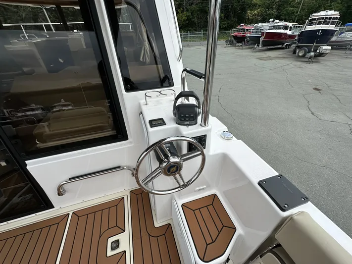  Yacht Photos Pics 2025 Ranger Tugs R29 S helm with modern controls and teak flooring, docked in a marina.