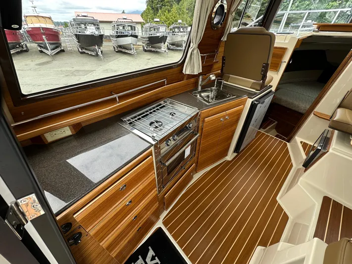  Yacht Photos Pics 2025 Ranger Tugs R29 S interior with modern kitchen, wood finish, and outdoor view.