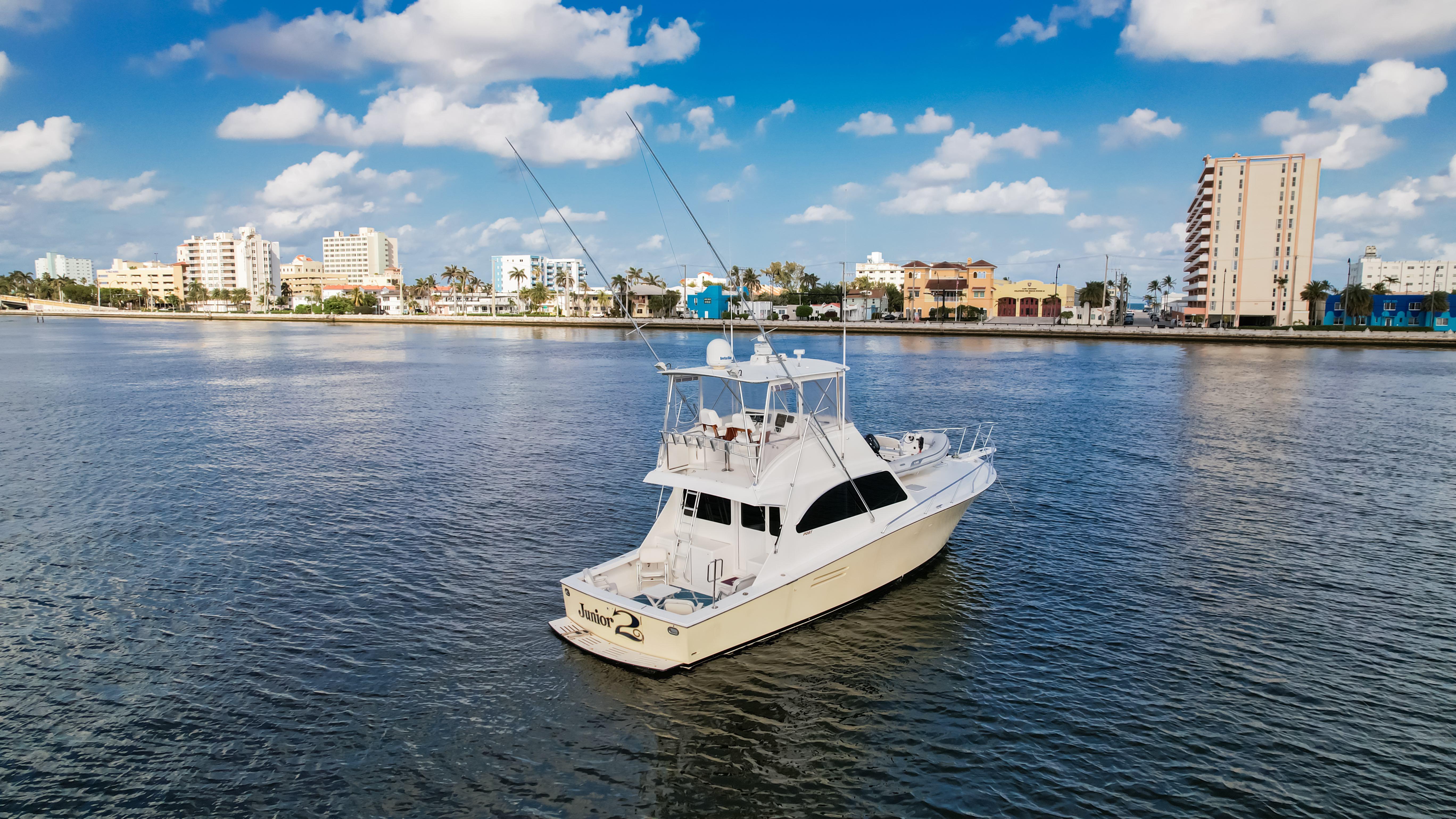 A 2008 Post 42 yacht on calm waters with a cityscape background under a blue sky.