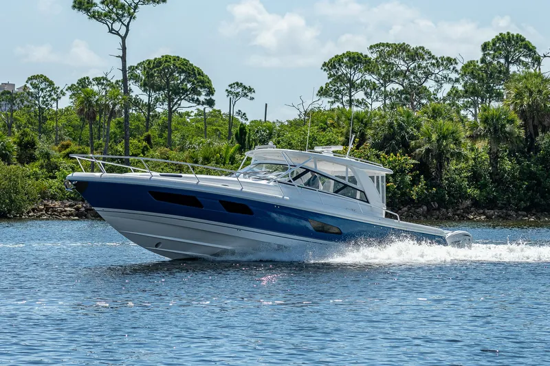  Yacht Photos Pics 2020 Intrepid 477 Evolution cruising on a sunny day near a lush shoreline.