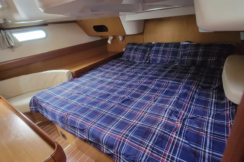  Yacht Photos Pics Cozy cabin interior of 2008 Jeanneau Sun Odyssey 42 DS with plaid bedding.