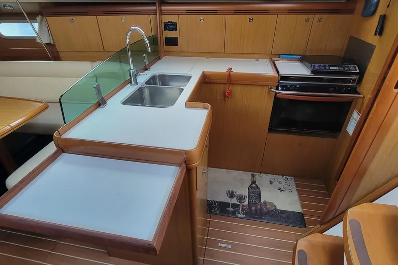  Yacht Photos Pics 2008 Jeanneau Sun Odyssey 42 DS yacht kitchen with sink, stove, and wooden cabinetry.