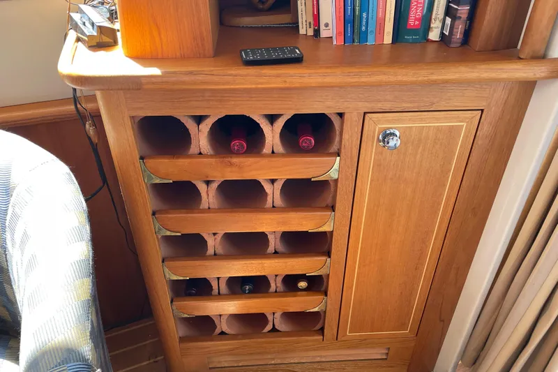  Yacht Photos Pics Wooden wine rack and cabinet on a 2007 Fathom Yachts 40, with books and remote.