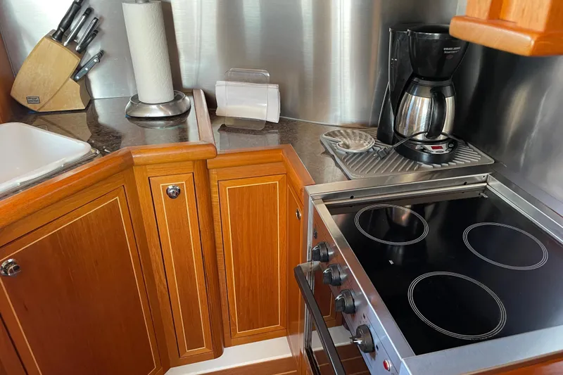  Yacht Photos Pics Compact kitchen in 2007 Fathom Yachts 40 with stove, coffee maker, and wooden cabinetry.