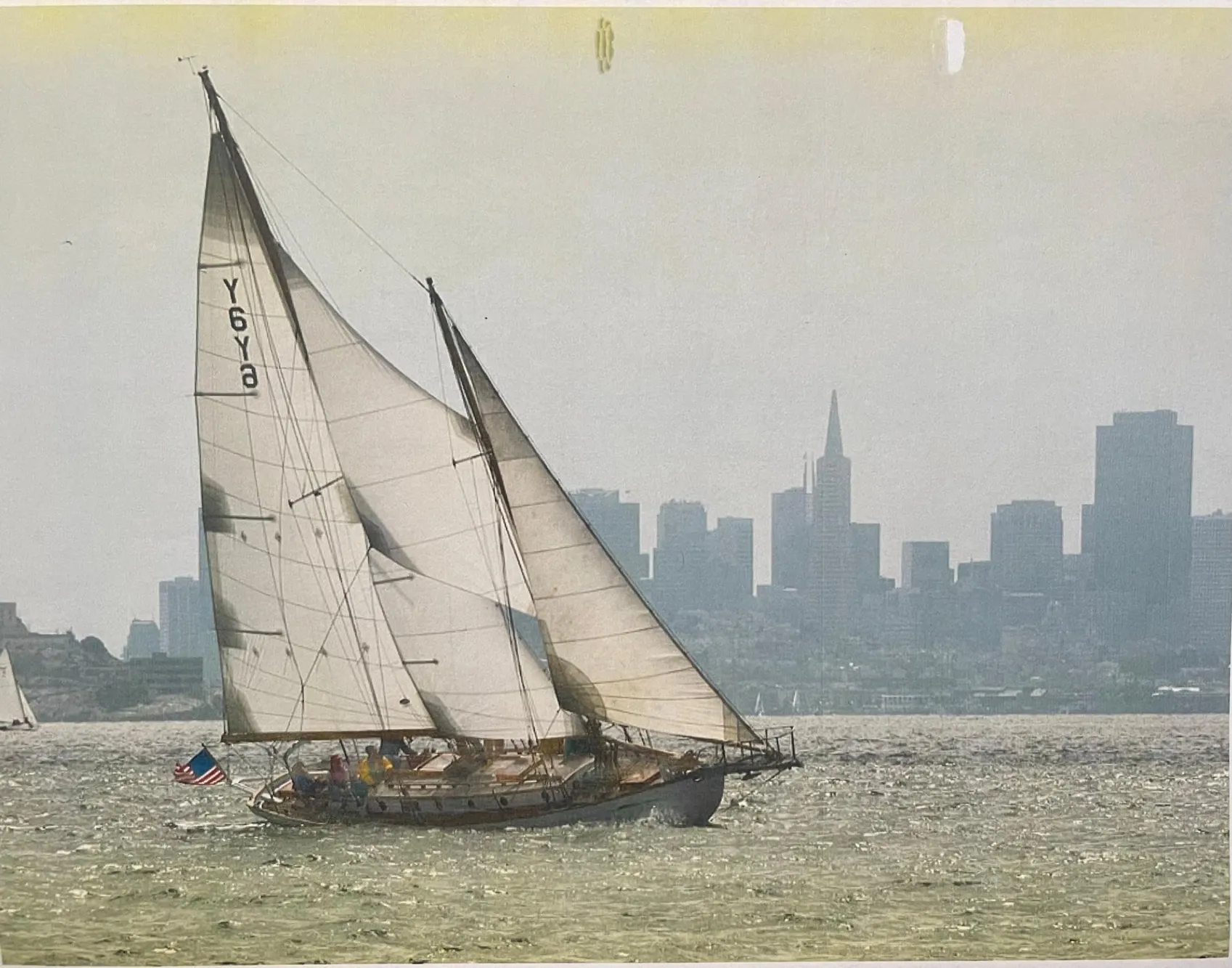 Vintage 1927 Schock Staysail Schooner sailing with city skyline backdrop.