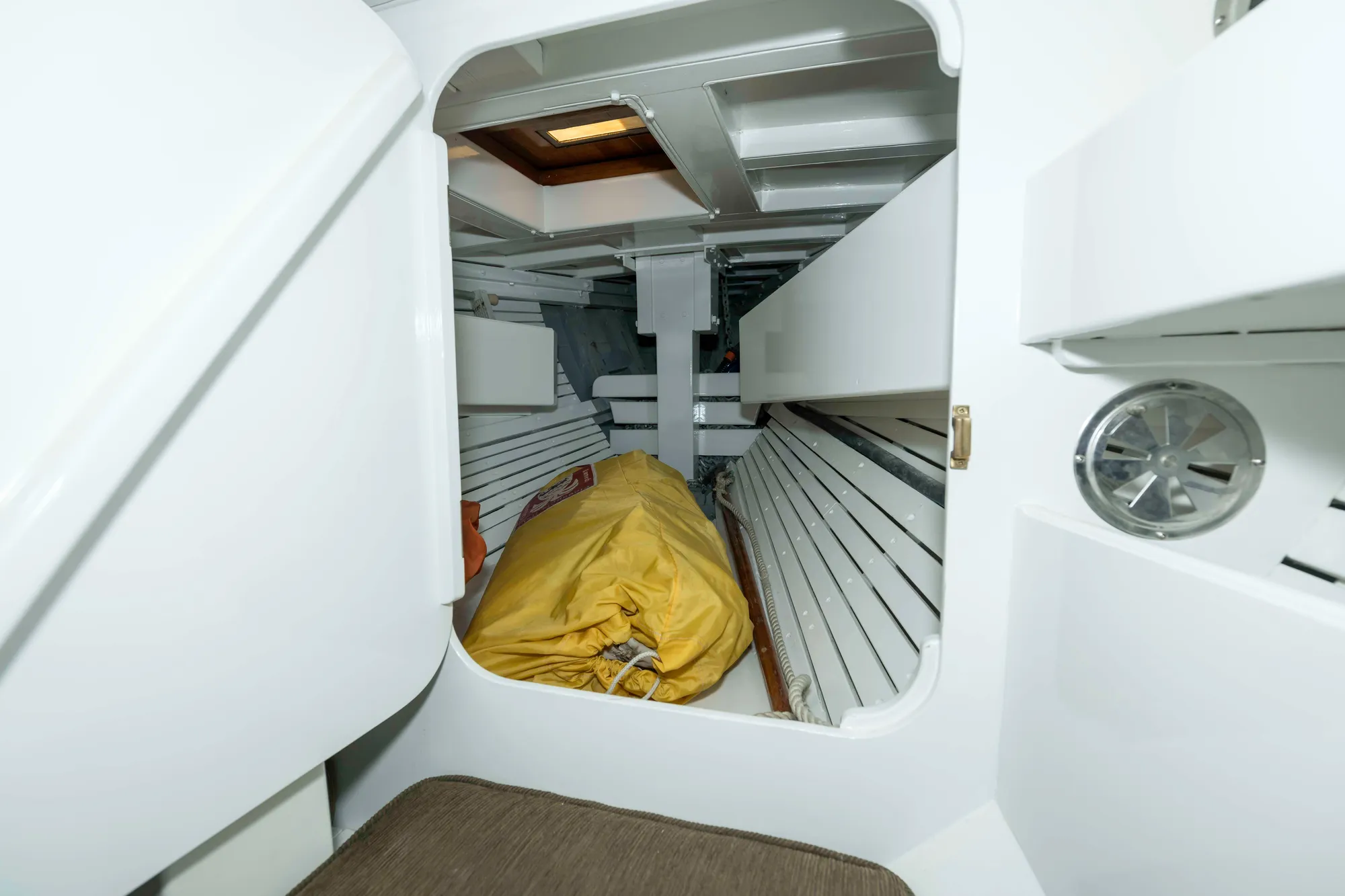Interior of 1927 Schock Staysail Schooner with white wooden benches and yellow sail bag.