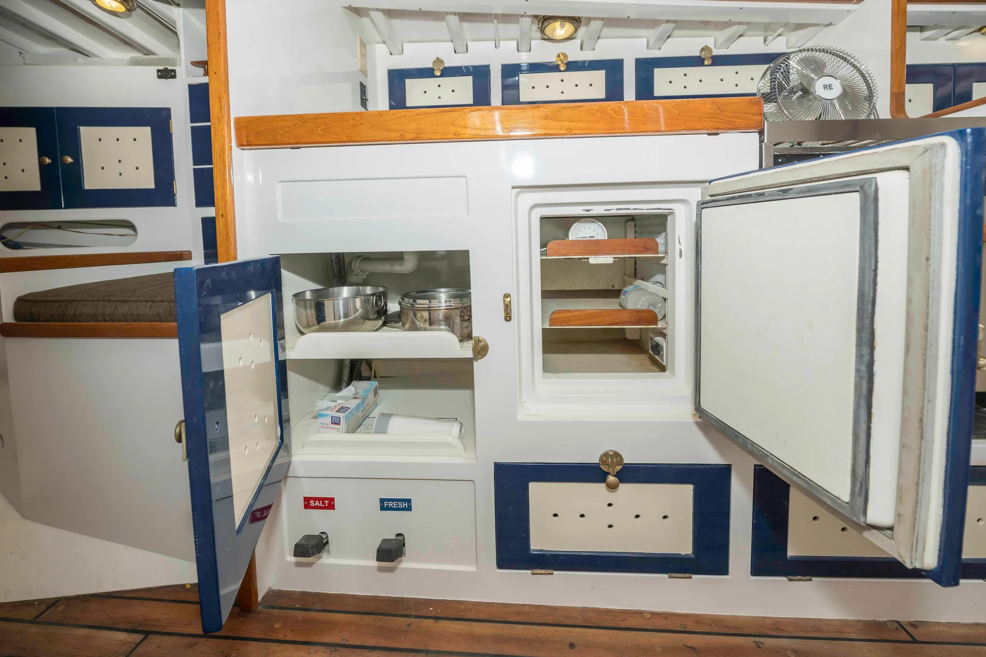 Interior of 1927 Schock Staysail Schooner with open cabinets and wooden flooring.