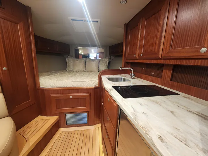  Yacht Photos Pics Luxurious interior of 2015 Jupiter 41 SB yacht with wood cabinetry and cozy sleeping area.