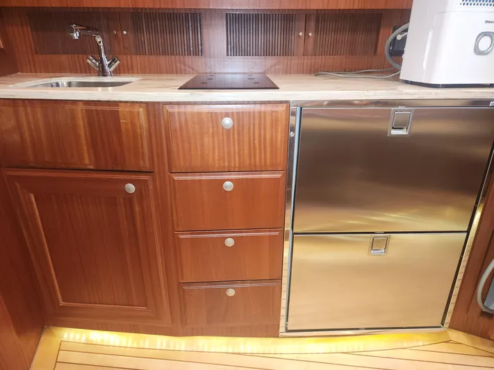  Yacht Photos Pics Wooden yacht kitchen with stainless steel appliances, featuring sink and storage. Jupiter 41 SB, 2015 model.