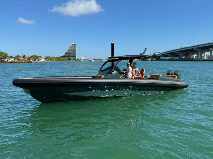 New 2025 Skipper 38 Twin 400 V10 Yacht Photos Pics 2025 Skipper-BSK 38 boat cruising on a sunny day near a bridge and cityscape.