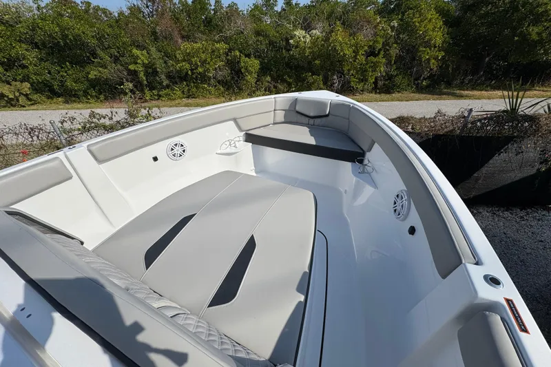  Yacht Photos Pics 2026 Monterey Elite 25 OB boat interior with cushioned seating and speakers, surrounded by greenery.