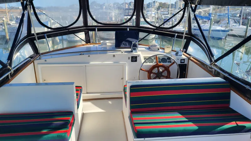Maia Yacht Photos Pics 1989 Grand Banks 42 Classic yacht interior with striped seating and wooden steering wheel.