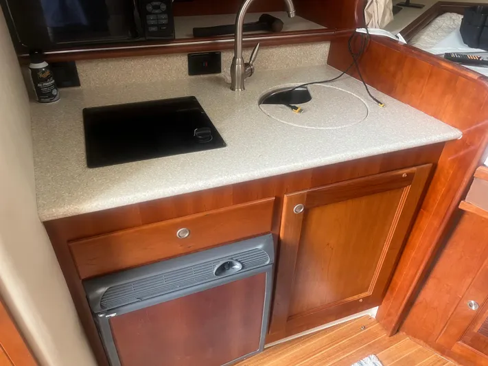  Yacht Photos Pics 2008 Rampage 30 Express boat kitchen with sink, stove, and wooden cabinetry.