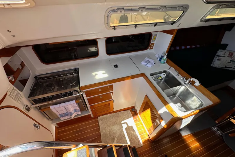 Ma Jolie Yacht Photos Pics Interior of 1996 J Boats J/120 sailboat featuring a compact kitchen with stove and sink.