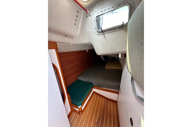 Ma Jolie Yacht Photos Pics Interior cabin of 1996 J Boats J/120 sailboat with wooden flooring and cozy sleeping area.