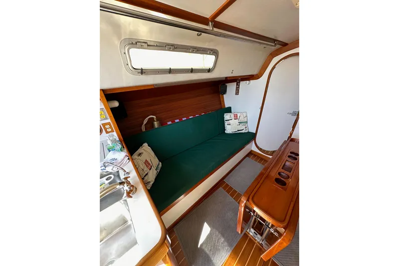 Ma Jolie Yacht Photos Pics Interior of 1996 J Boats J/120 sailboat with green cushioned seating and wooden accents.