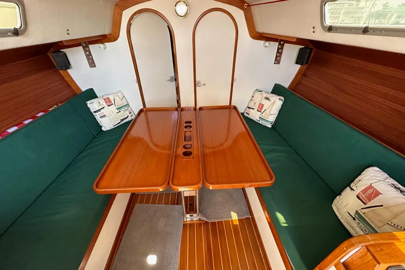 Ma Jolie Yacht Photos Pics Interior of 1996 J Boats J/120 sailboat with wooden table and green seating.