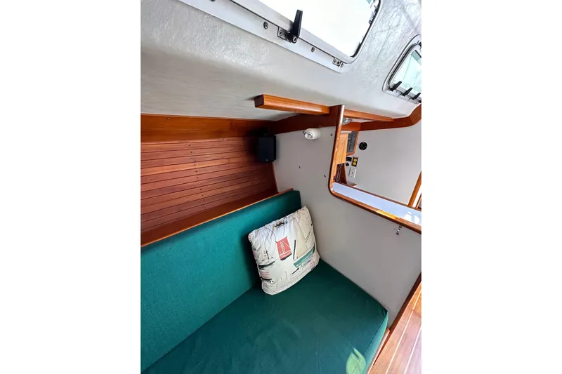 Ma Jolie Yacht Photos Pics Interior of 1996 J Boats J/120 sailboat with green cushion and nautical-themed pillow.