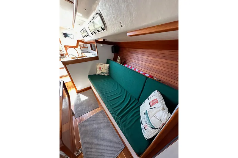 Ma Jolie Yacht Photos Pics 1996 J Boats J/120 interior with green cushioned seating and nautical-themed pillows.