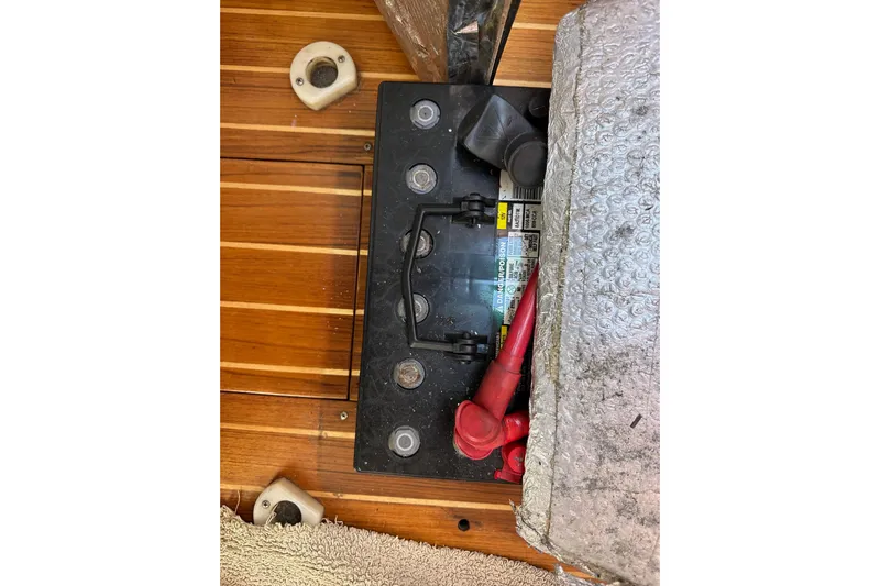 Ma Jolie Yacht Photos Pics Battery compartment of a 1996 J Boats J/120 sailboat with red cables and wooden flooring.